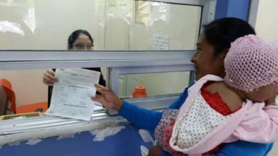 Una madre registra a su bebé en la ventanilla del hospital.