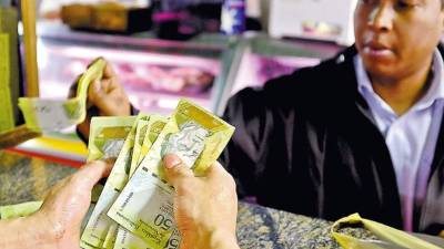 Un cajero cuenta bolívares en una carnicería en un mercado de Caracas.