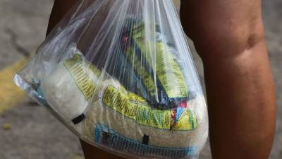 Una mujer camina con una bolsa con alimentos básicos distribuidos en el barrio 23 de Enero en Caracas.