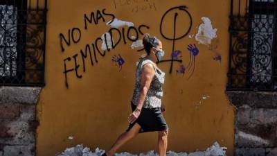 Una mujer camina frente a un mural que dice 'no más feminicidios', en la pared de un edificio en Centro Histórico, en Tegucigalpa(Honduras).