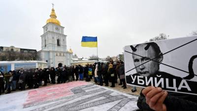 Un manifestante sostiene un cartel que representa al presidente ruso Vladimir Putin, firmado “asesino” durante una acción denominada #SayNOtoPutin en Kiev.