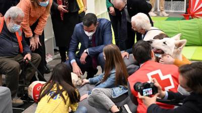 El presidente del Gobierno de España, Pedro Sánchez (centro), habla con niños y miembros de la Cruz Roja Española que asisten a terapia con perros, durante su visita a un centro de recepción para refugiados ucranianos.