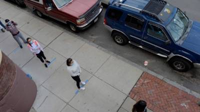 Personas cumplen con el distanciamiento social mientras hacen fila para recibir alimentos. Foto: AFP