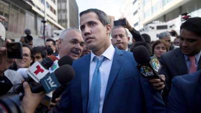 El líder opositor venezolano Juan Guaidó (c), rodeado de miembros de la prensa, se retira de las inmediaciones del Palacio Federal Legislativo luego de que miembros de la policía y de la Guardia Nacional Bolivariana le impidieran entrar a la sesión de la Asamblea Nacional este domingo, en Caracas (Venezuela).