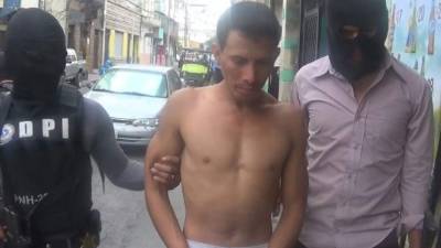 Un hombre es custodiado por dos agentes de la Dirección Policial de Investigaciones (DPI).