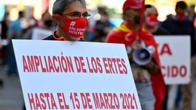 Un manifestante sostiene un cartel exigiendo una extensión del esquema de licencia del gobierno en apoyo en medio de la pandemia de coronavirus. Foto AFP