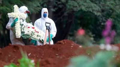 Empleados del servicio funerario entierran a una víctima de COVID-19 en el cementerio de Vila Formosa, situado en Sao Paulo (Brasil).