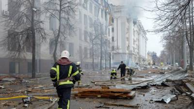 Los bomberos trabajan para contener un incendio ante edificio atacado durante el reciente bombardeo de Rusia.