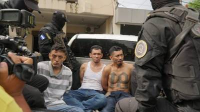 Agentes custodiando a los tres supuestos pandilleros arrestados esta mañana.