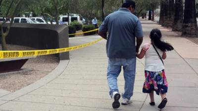 Un hombre camina junto a su hija tras salir de una cita en la Oficina de Control de Inmigración y Aduanas (ICE), en centro de Phoenix, Arizona (EE.UU.).