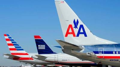 Los aviones de US Airways y American Airlines se sientan en la terminal después de que las aerolíneas anunciaran la fusión de las dos aerolíneas.