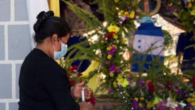 Una mujer enciende una vela frente a un altar improvisado con una replica de la Virgen de Suyapa hoy en Tegucigalpa (Honduras).