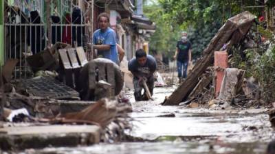 Personas limpian sus viviendas tras las inundaciones que dejó a su paso Iota, en la localidad de La Lima.