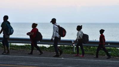 Migrantes hondureños caminan por una carretera que bordea el mar Caribe en Omoa, yendo desde San Pedro Sula a Corinto, Honduras, en la frontera con Guatemala, como parte de una nueva caravana que se dirige a los EE. UU.