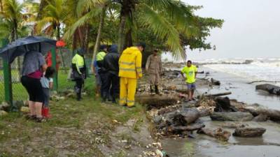 Personal del Cuerpo de Bomberos inspeccionan el lugar en donde se halló el cadáver de una persona en la orilla de una playa en Omoa, Cortés.