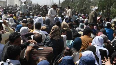 Los afganos se reúnen al borde de la carretera cerca de la parte militar del aeropuerto de Kabul. Foto AFP