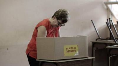 A supporter of the presidential candidate for the National Restoration Party (PRN), Fabricio Alvarado, passes by a banner depicting the presidential candidate for the Citizen Action Party (PAC), Carlos Alvarado, outside a polling station in San Jose on April 1, 2018 during Costa Rica's run-off election.Polling stations across Costa Rica opened early Sunday for a presidential election that has split the country between an ultra-conservative evangelical preacher who slams gay rights and a former minister from the center-left ruling party. / AFP PHOTO / Ezequiel BECERRA
