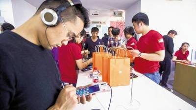 Los consumidores prueban distintos teléfonos de Xiaomi en el primer día del lanzamiento del esperado modelo Mi Note, que salió a la venta en mayo de 2015.