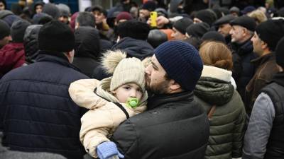 Un hombre sostiene a su hijo mientras las familias, que huyeron de Ucrania debido a la invasión rusa, esperan para ingresar a un campo de refugiados en la capital de Moldavia, Chisinau.