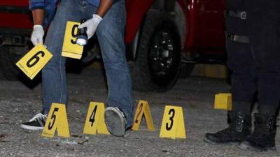 Policías inspeccionan una escena del crimen | Fotografía de archivo