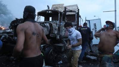 Manifestantes se enfrentan con miembros de la Policía Nacional Bolivariana, junto a un camión que transportaba ayuda humanitaria y fue quemado, este sábado, en el puente Francisco de Paula Santander, en la frontera entre Cúcuta (Colombia) y Venezuela. EFE