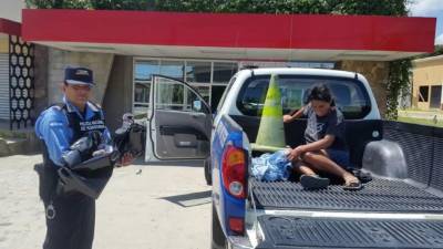 Un integrante de la Policía carga a un bebé después de que una mujer diera a luz a un bebé en plena vía pública en la ciudad de La Ceiba, Atlántida.