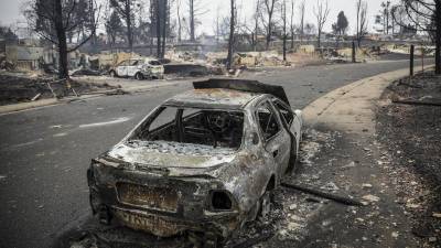 Los restos de un automóvil quemado se encuentran en medio de los restos de un vecindario después del incendio Marshall.