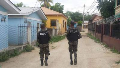 Dos elementos de la Policía Militar del Orden Público (PMOP) caminan por una calle, durante un operativo, en La Lima, Cortés.