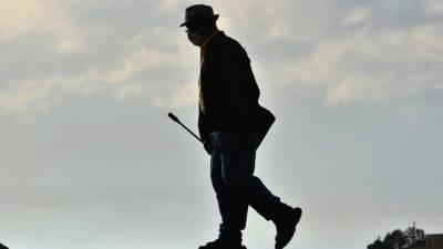 Foto referencial: Un adulto camina en las calles con su mascarilla de protección para prevenir el contagio en Honduras.