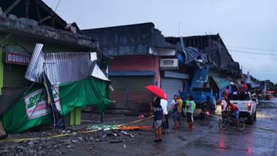 Los residentes observan una casa destruida con un vehículo apretado debajo de un terremoto de 6,8 grados de magnitud en la ciudad de Padada. Foto AFP