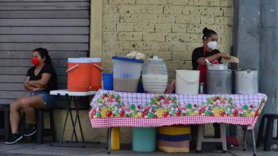 Un vendedor ambulante usa una máscara facial mientras prepara las tradicionales baleadas en Tegucigalpa. Foto AFP
