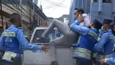 El periodista hondureño Bryan Hernández en el momento que es lanzado a la patrulla.