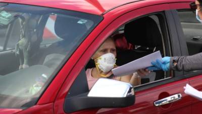 Una persona en su automóvil en EEUU recibe una solicitud de desempleo. Foto: AFP