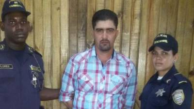 El detenido es custodiado por dos agentes de la Policía Nacional de Honduras.