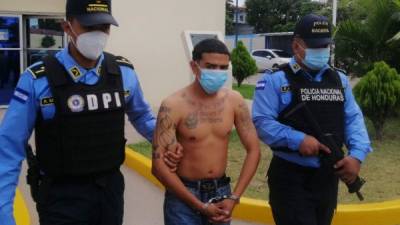 Jhonny Ariel López Mejía siendo custodiado por dos agentes.