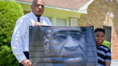 Mallory Jackson y su hijo Mikhail Jackson, de 10 años, posan con un cartel en honor a George Floyd en Houston. Foto: AFP