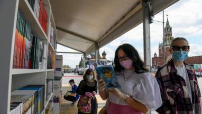 Los visitantes que usan máscaras protectoras miran los libros que se exhiben en un stand durante la feria anual del libro en la Plaza Roja en el centro de Moscú. Foto AFP