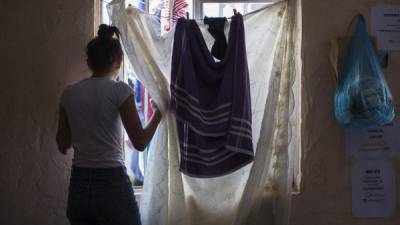 Una migrante centroamericana mira hacia la ventana en el refugio donde permanece.