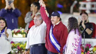 El presidente de la Asamblea Nacional de Nicaragua, Gustavo Porras, levantando la mano del presidente nicaragüense Daniel Ortega mientras presta juramento como presidente por cuarto mandato consecutivo junto a su esposa y vicepresidente Rosario Murillo.