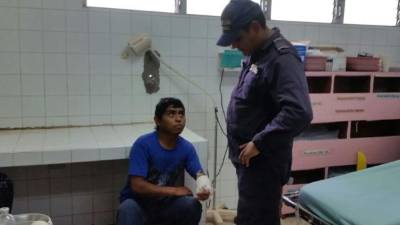 El detenido es custodiado por un agente de la Policía Nacional de Honduras.