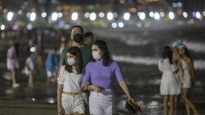 La gente camina sobre una playa en la víspera de Año Nuevo.