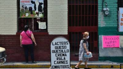 Una mujer compra productos lácteos en una tienda en Tegucigalpa durante la nueva pandemia de coronavirus COVID-19. Foto AFP