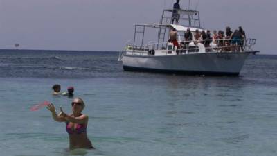 Turistas de diferentes nacionalidades disfrutando de una de las playas de la isla de Roatán en el Caribe hondureño.