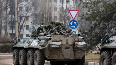 Los militares viajan sobre un vehículo blindado ruso. Explosiones antes del amanecer en Kiev desencadenaron un segundo día de violencia.