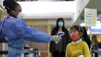 Una sanitaria tomaba la temperatura a una niña procedente de China, en el aeropuerto internacinal de Nairobi, el pasado 29 de enero.