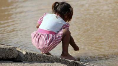 Fotografía del 30 de noviembre de 2020 de una niña que juega en aguas estancadas dejadas por las inundaciones causadas por las tormentas tropicales Eta y Iota en la comunidad de Omonita al norte de Honduras.