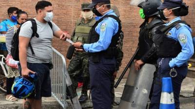 Oficiales y soldados interceptan en la calle a un hombre, todos con máscaras faciales como medida preventiva contra la propagación del nuevo coronavirus. Foto AFP
