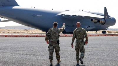 Personal estadounidense caminando cerca de un avión militar en una instalación militar. Foto AFP