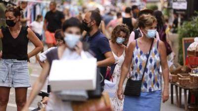Las personas que usan mascarillas protectoras compran a lo largo de la calle Fesch, en el distrito turístico de Ajaccio. Foto AFP