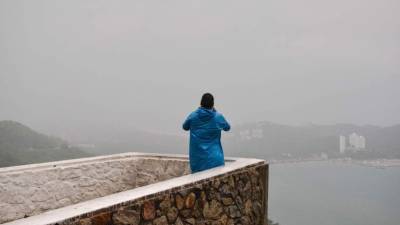 Un hombre toma fotos de la lluvia y los efectos de fuertes vientos en Guerrero, México. AFP